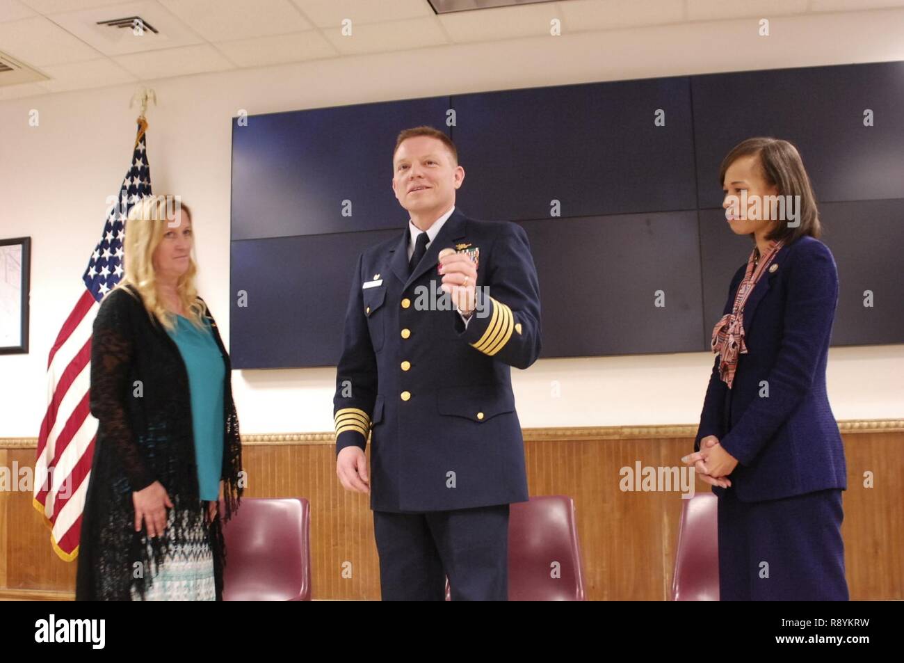 Capt. Benjamin Cooper, commander of Sector Delaware Bay, illustrates Ms. Jacquelyn Hamilton's heroic actions that resulted in saving a woman's life with Rep. Lisa Blunt Rochester at Sector Delaware Bay, Philadelphia, March 13, 2017.    Hamilton was recognized for saving the life of a woman on a passenger vessel on June 11, 2016. While underway, a passenger began to suffer from fainting spells and soon collapsed. Ms. Hamilton quickly alerted the captain of the vessel to head back to port and she then performed CPR, ultimately saving the woman's life. Stock Photo