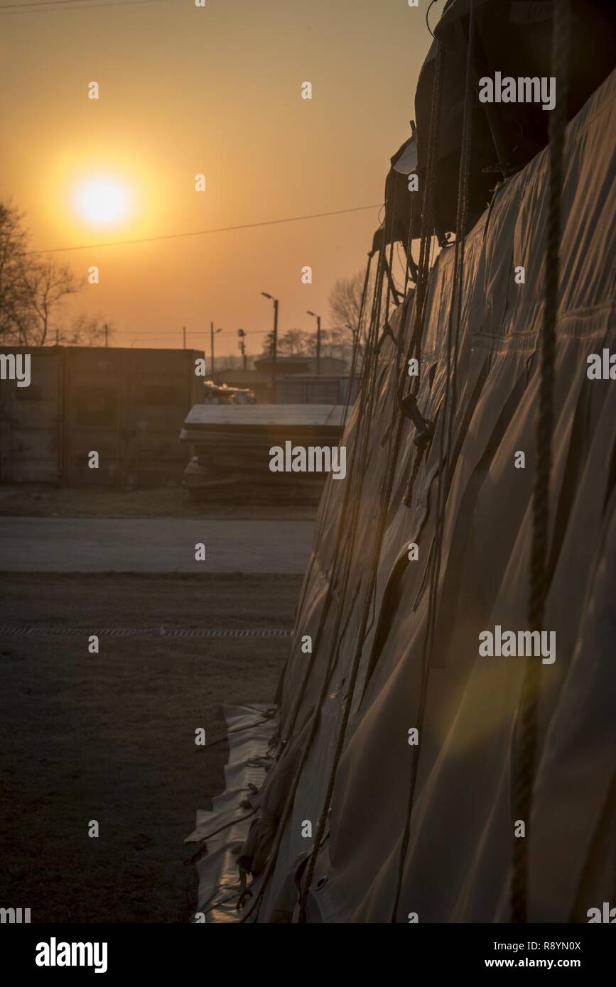 A tent’s ropes used to secure the weather fly whip around in the evening’s breeze in the Rush Park life support area at Osan Air Base, Republic of Korea, March 14, 2017. Rush Park is home to 24 tents and several K-span buildings. Each tent can house up to 20 personnel and the K-spans have room for 120 personnel. The LSA’s Services Sustainment Flight arrived about a week before the main body involved with Key Resolve 2017. From boots on the ground, the LSA’s construction took just 72 hours to build and ready to receive the first bus load of personnel. Stock Photo