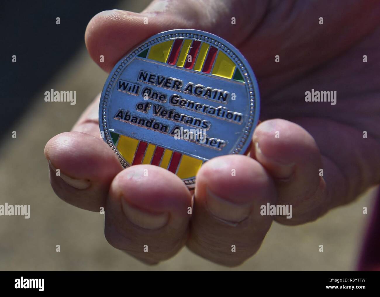 Retired U.S. Air Force Capt. William Robinson, longest surviving enlisted prisoner of war, holds a Vietnam veteran coin after an award ceremony here, March 17, 2017. Robinson was a POW for nearly eight years before being released. Now, Robinson speaks about his experience with community and military members across the country. Stock Photo