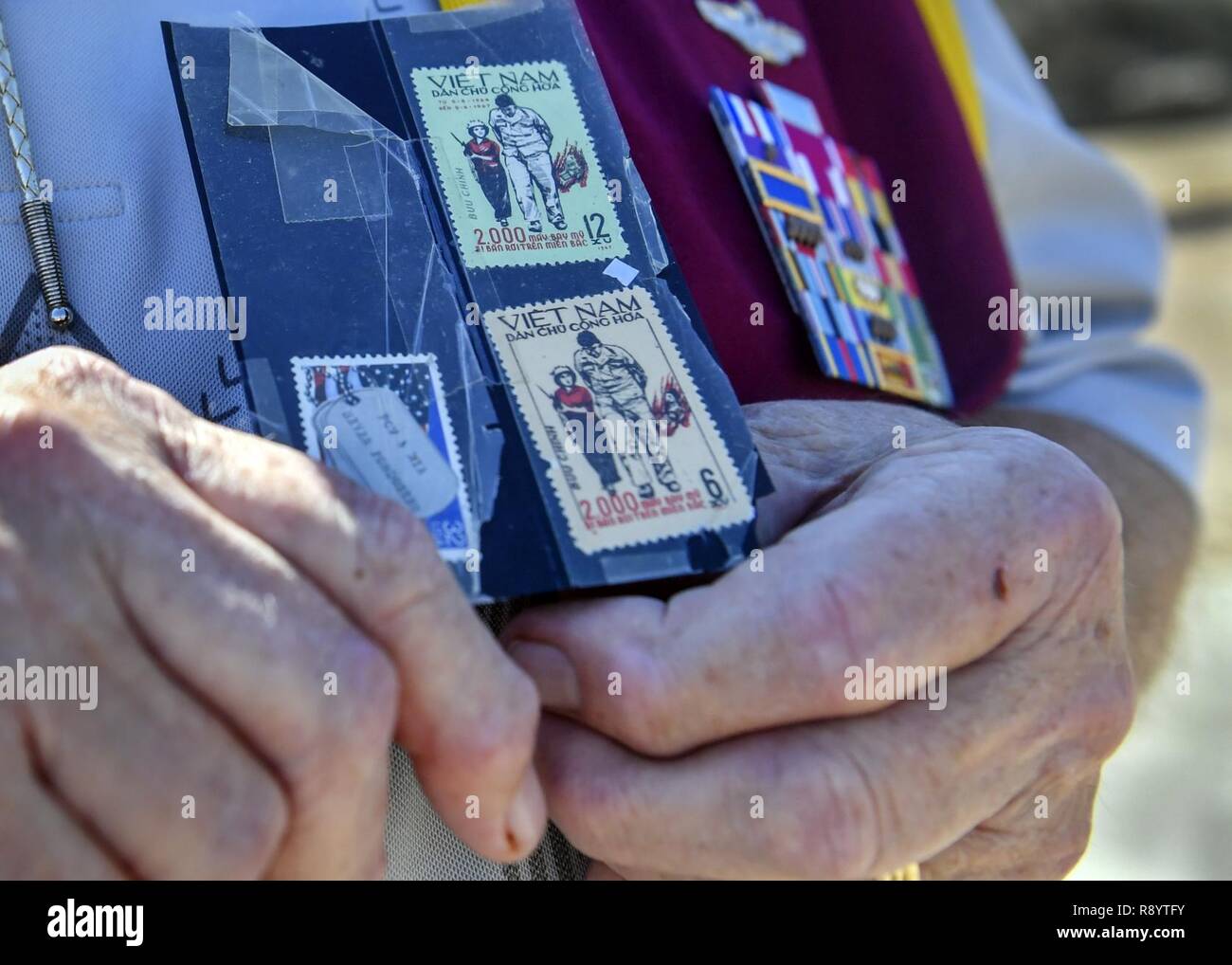 Retired U.S. Air Force Capt. William Robinson, longest surviving enlisted prisoner of war, holds a stamp, depicting him and a Vietnamese woman, used for propaganda after an award ceremony here, March 17, 2017. Robinson was a POW for nearly eight years before being released. Now, Robinson speaks about his experience with community and military members across the country. Stock Photo