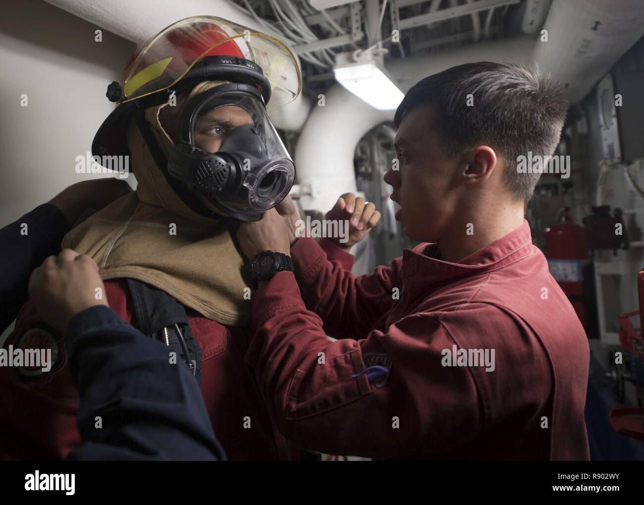 SOUTH CHINA SEA (March 13, 2017) Gas Turbine System Technician (Mechanical) 2nd Class Jonathan Young, right, helps Damage Controlman 3rd Class Robert Bridges don his firefighting gear during a damage control fire drill aboard the Arleigh Burke-class guided-missile destroyer USS Michael Murphy (DDG 112). The ship is on a western Pacific deployment with the Carl Vinson Carrier Strike Group as part of the U.S. Pacific Fleet-led initiative to extend the command and control functions of U.S. 3rd Fleet. Stock Photo