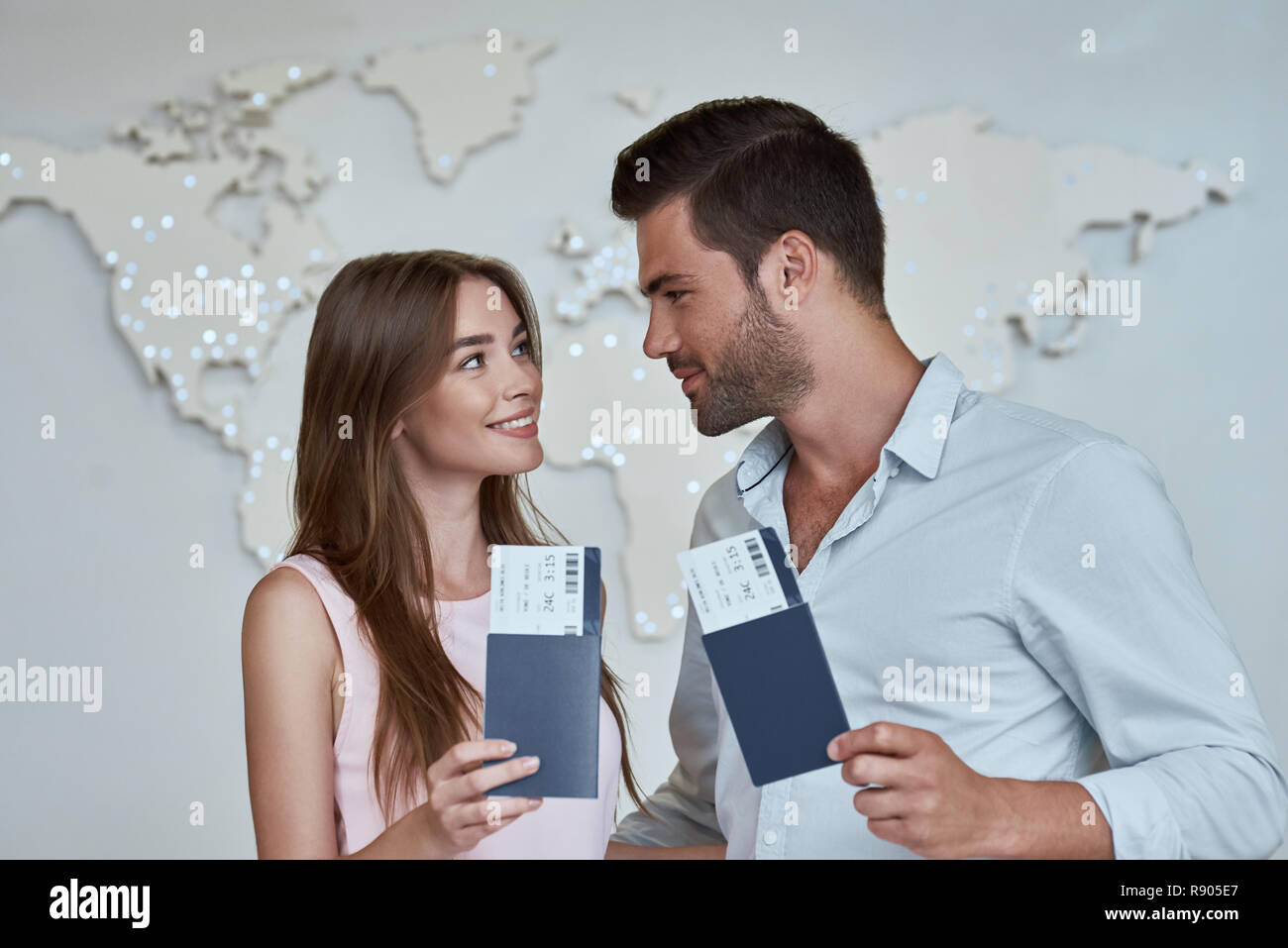 Joyful couple looking to each other and holding passport with flying