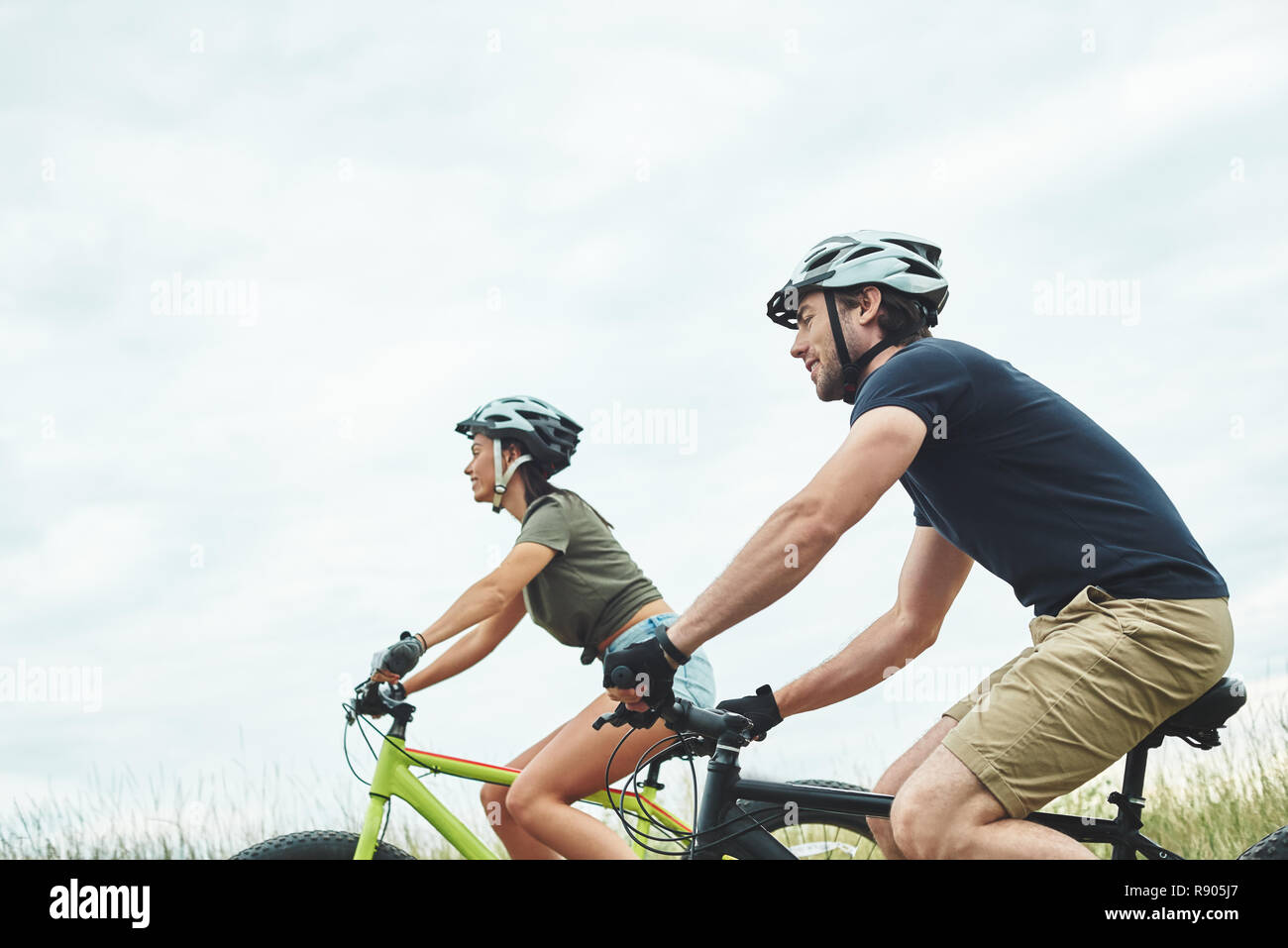 Young couple are cycling on fatbikes and in helmets. Cropped photo Stock Photo