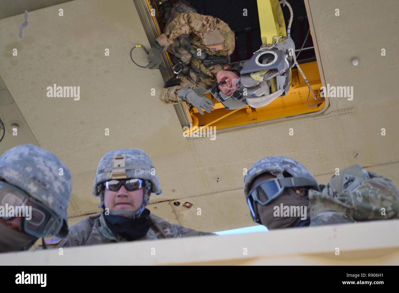 Spc. Dylan McNatt, upper center, assigned to the 2nd Battalion, 501st Aviation Regiment, Combat Aviation Brigade, 1st Armored Division, delivers communications from the bottom of a CH-47 Chinook as it hovers above a Conex box during sling load training at Biggs Army Airfield here Friday. Cpl. Andres Rios, in sunglasses, assigned to Headquarters and Headquarters Company, Special Troops Battalion, 1st Armored Division Sustainment Brigade, prepares to climb off the box with two fellow Soldiers. Stock Photo