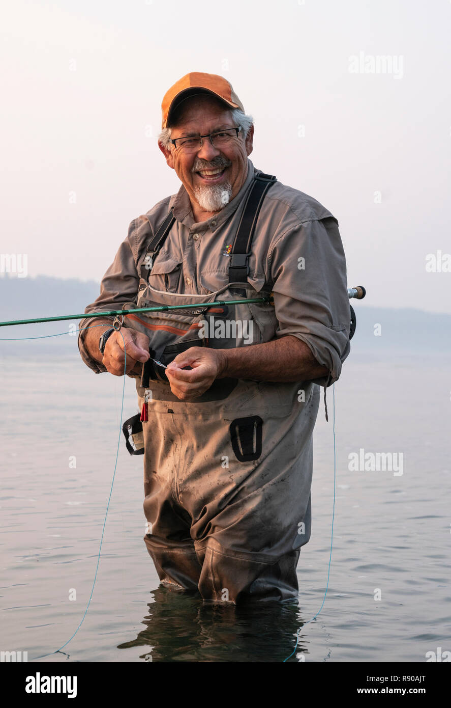 Caucasian senior male tying a fly on his fly fishing line while