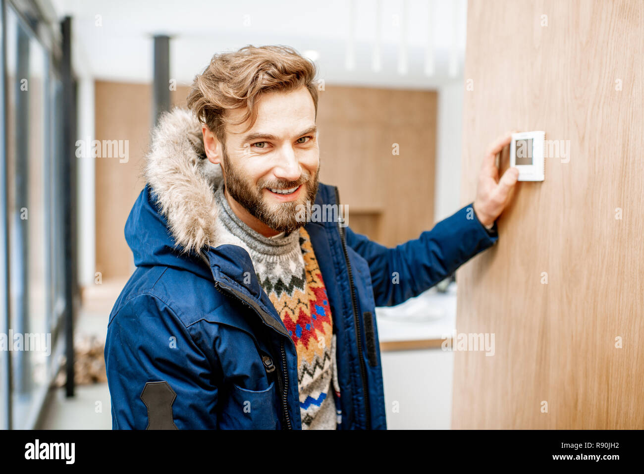 https://c8.alamy.com/comp/R90JH2/man-in-winter-clothes-feeling-cold-adjusting-room-temperature-with-electronic-thermostat-at-home-R90JH2.jpg