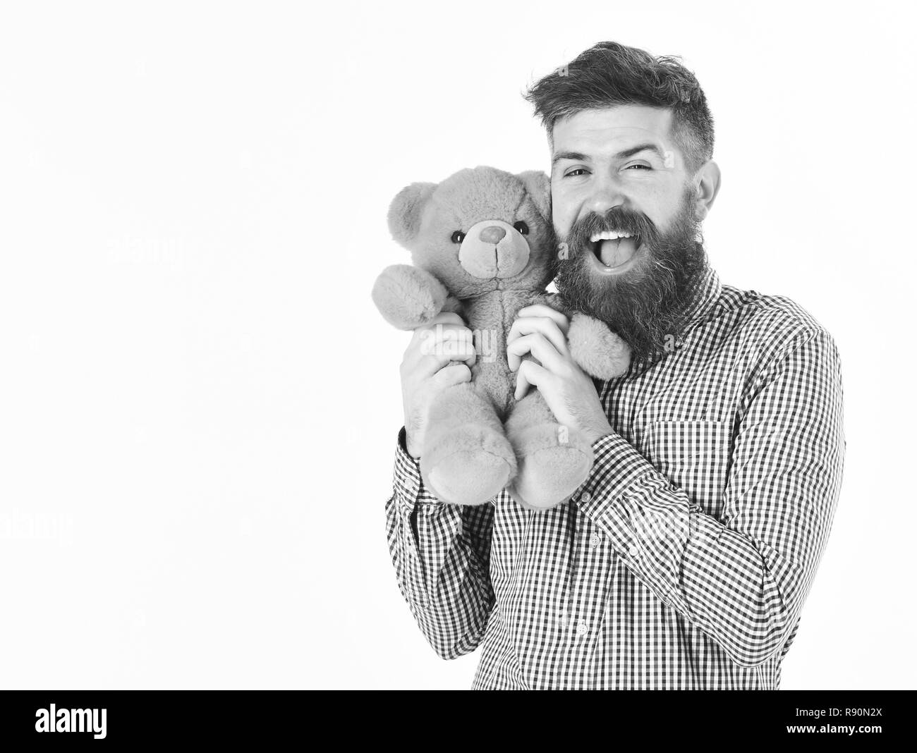 Hipster or father with soft toy as gift or present. Gifts and holidays concept. Macho with beard presents plush toy. Man with cheerful expression holds cute teddy bear, isolated on white background. Stock Photo