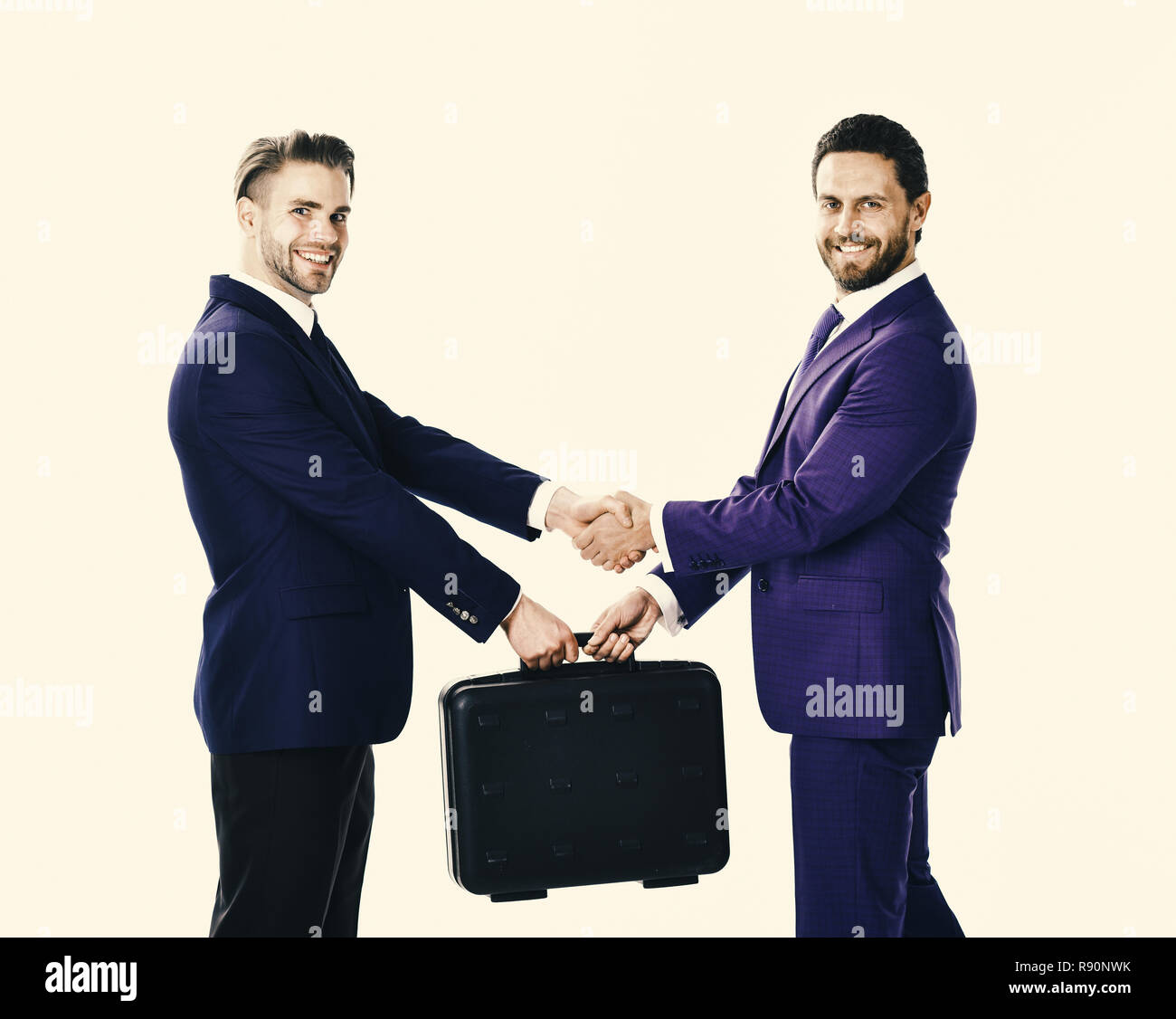 Handover of suitcase in hands of partners on white background