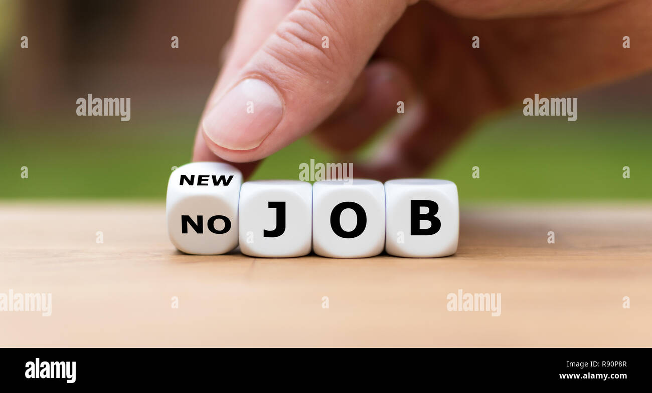 Hand is turning a dice and changes the expression 'no job' to 'new job' Stock Photo