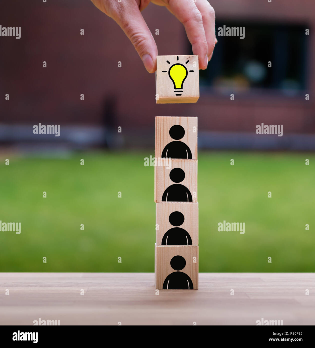 Teamwork brings the idea, symbolized by a stack of cubes with people icons Stock Photo