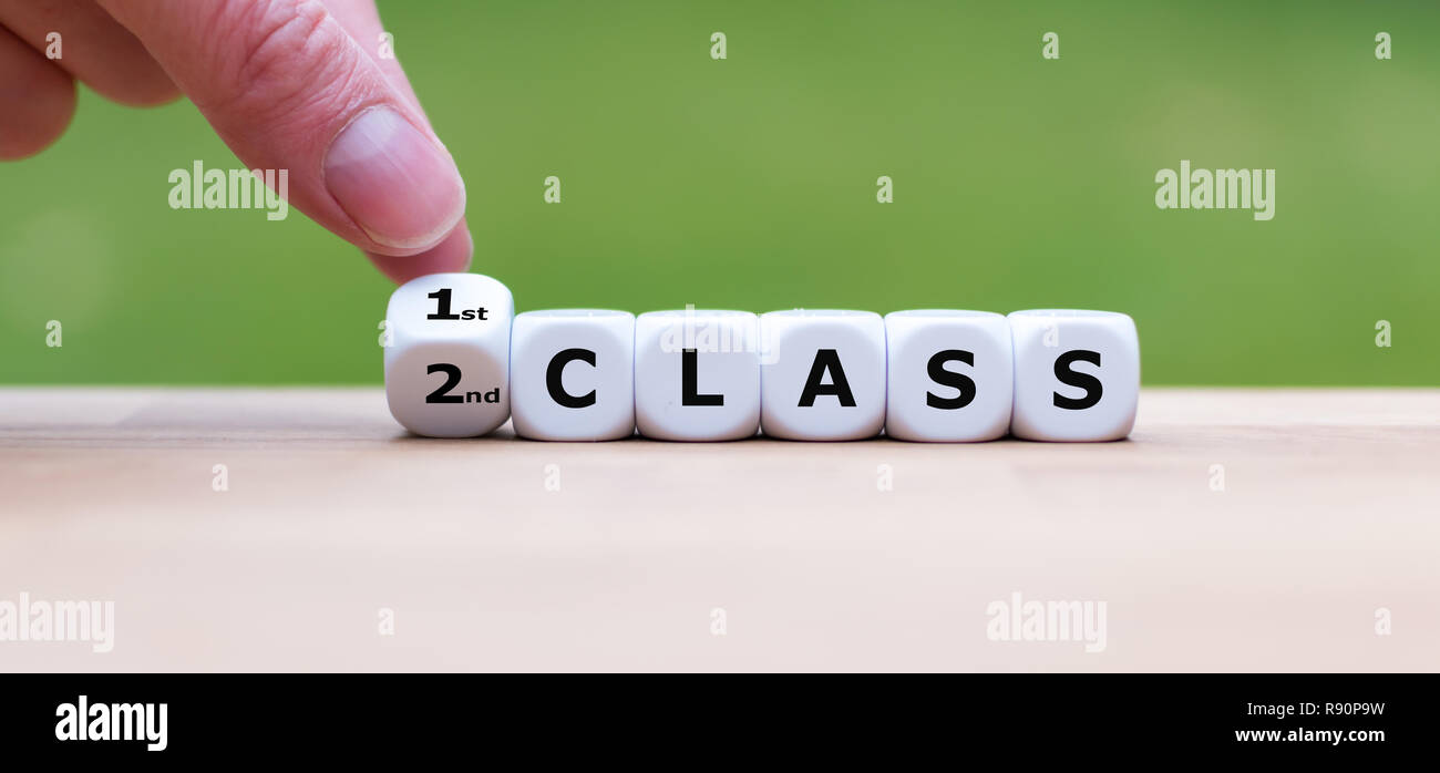 Hand is turning a dice and changes the word '2nd Class' to '1st Class' Stock Photo