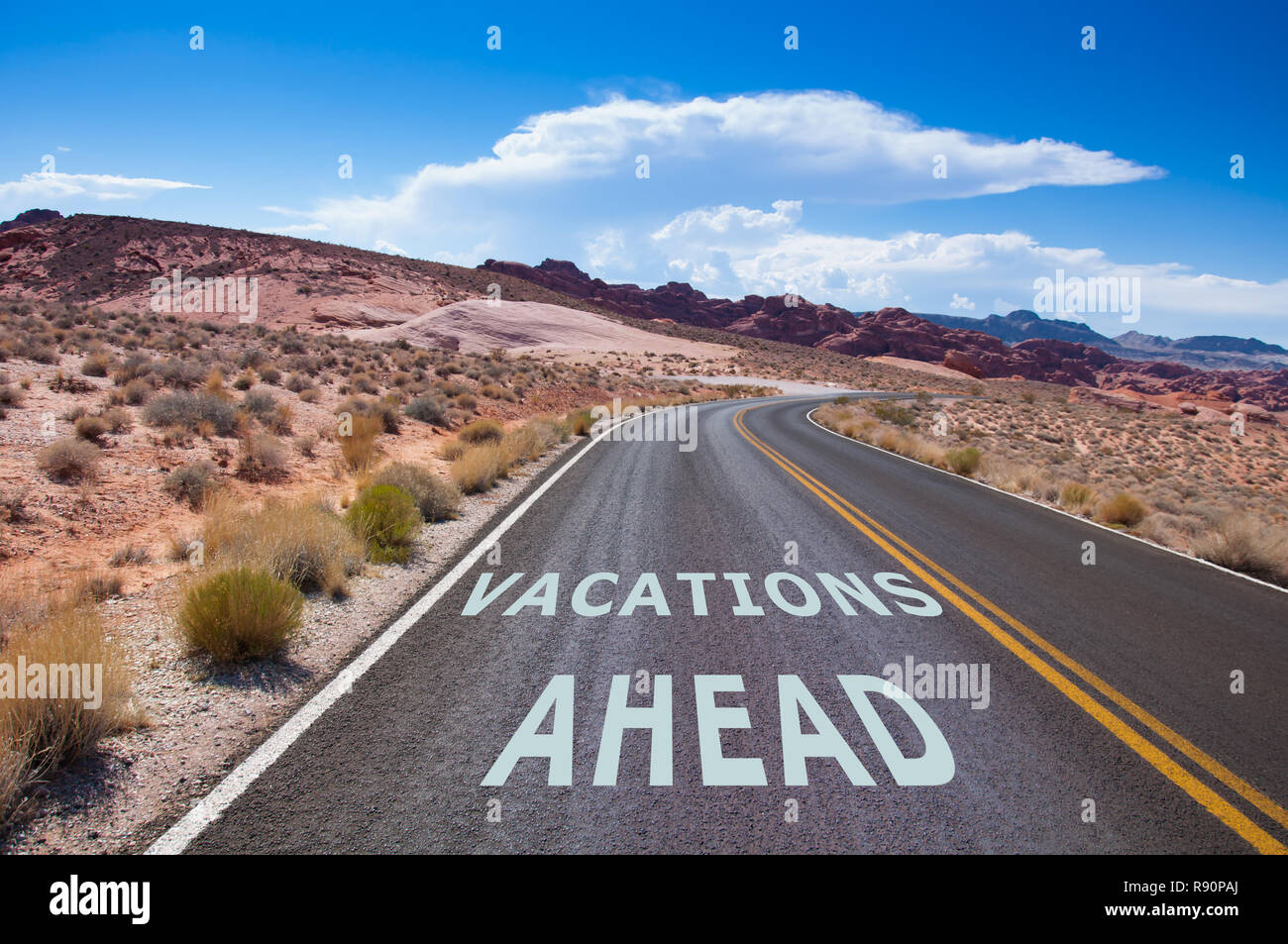 The text 'Vacations ahead' written on a empty road in the desert of Nevada before the street turns right Stock Photo