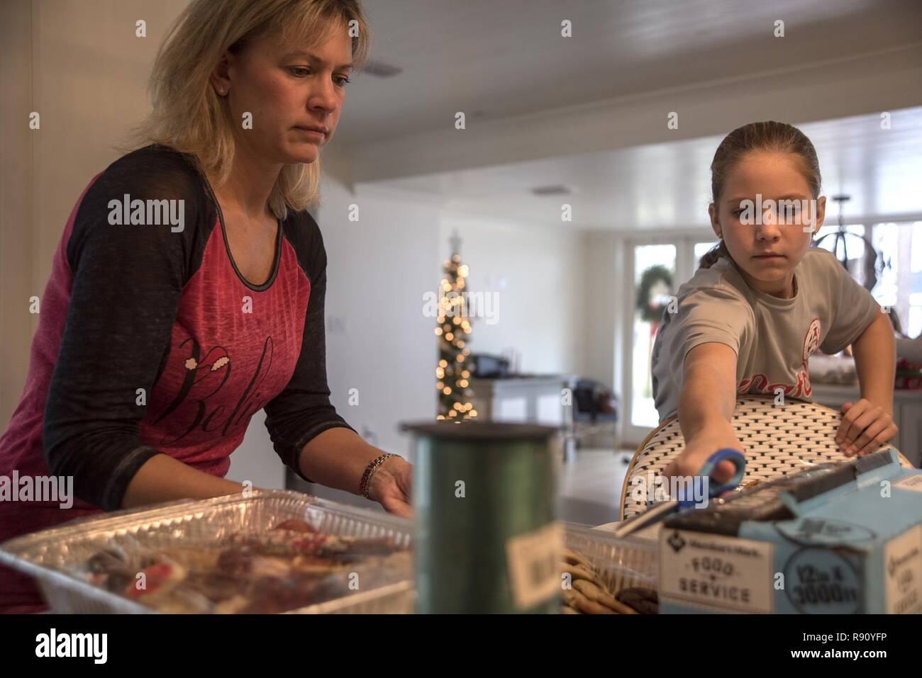Samantha and Taylor Laidlaw put cellophane on the tin containers of cookies Dec. 9, 2018, in Panama City, Fla. The spouses club collected more than 300 dozen cookies that will be disseminated to Airmen throughout Tyndall as part of this 2018’s cookie caper. Stock Photo