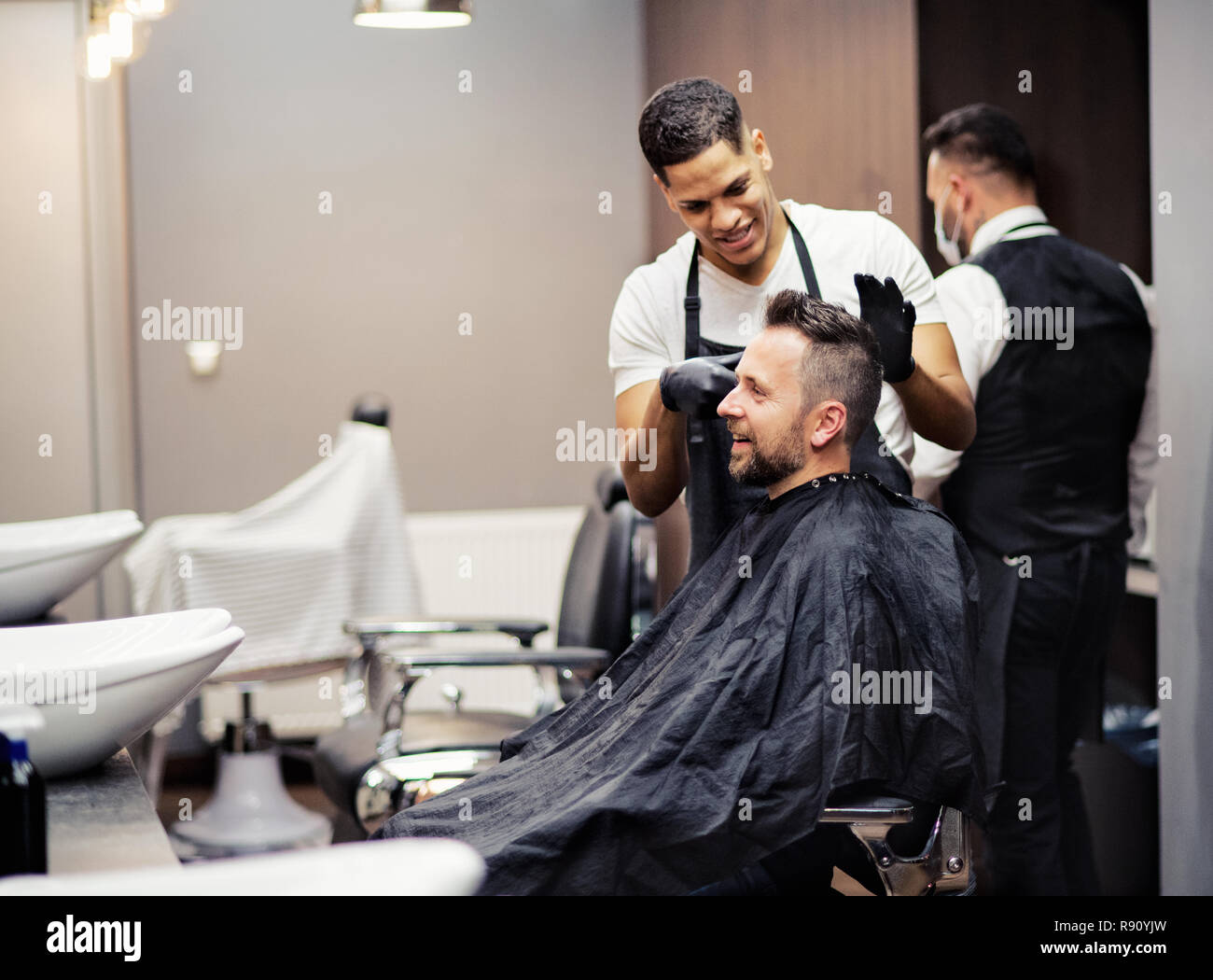 A hipster man client visiting haidresser and hairstylist in barber shop. Stock Photo