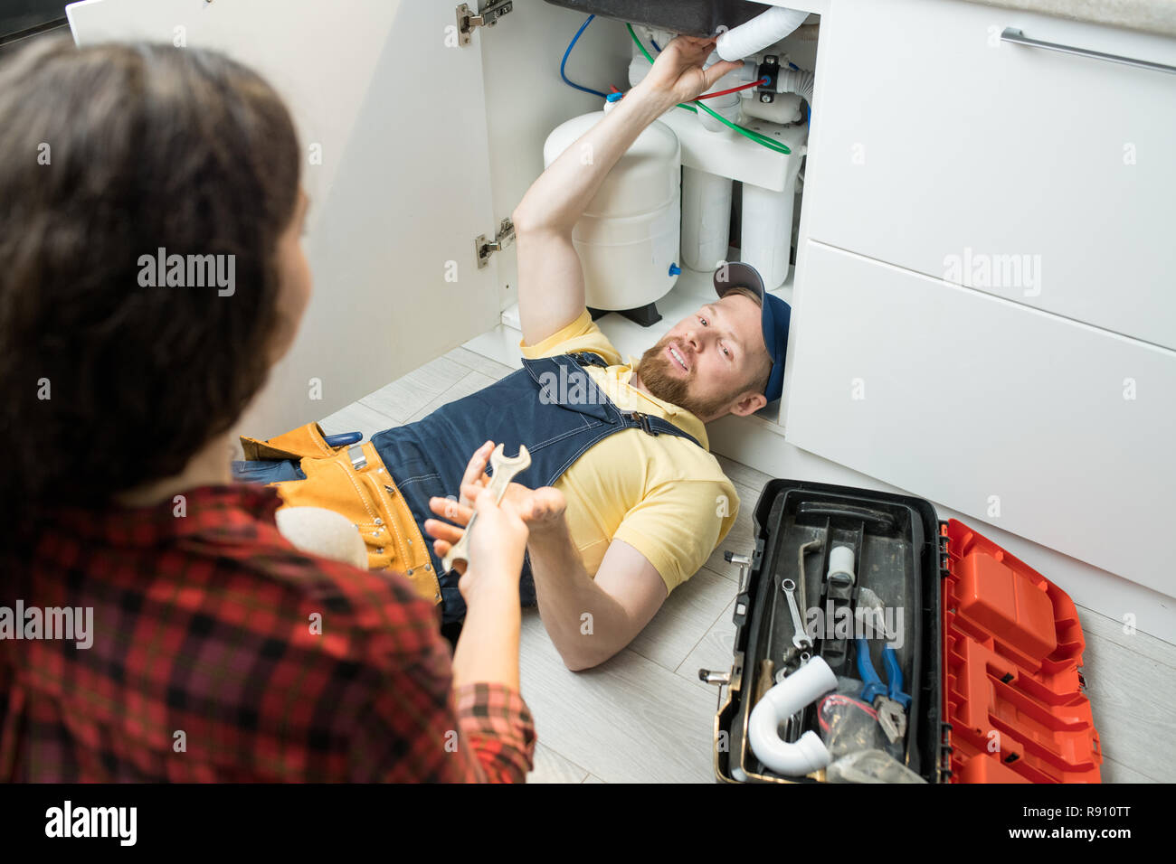 Handsome plumber fixing sink pipe Stock Photo