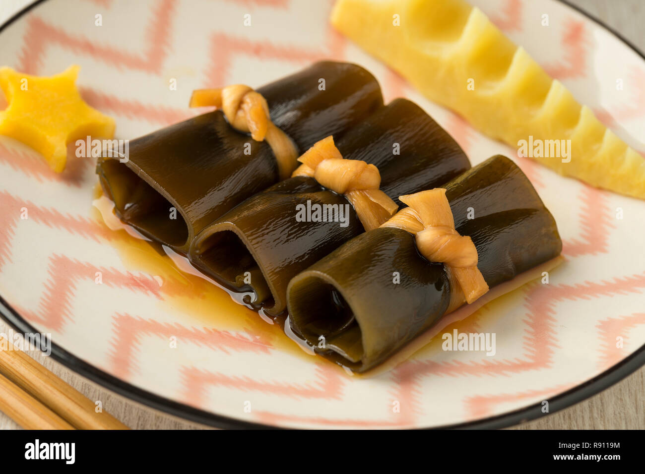 Traditional simmered kelp rolls, kobumaki, on a dish with bamboo shoot and carrot Stock Photo
