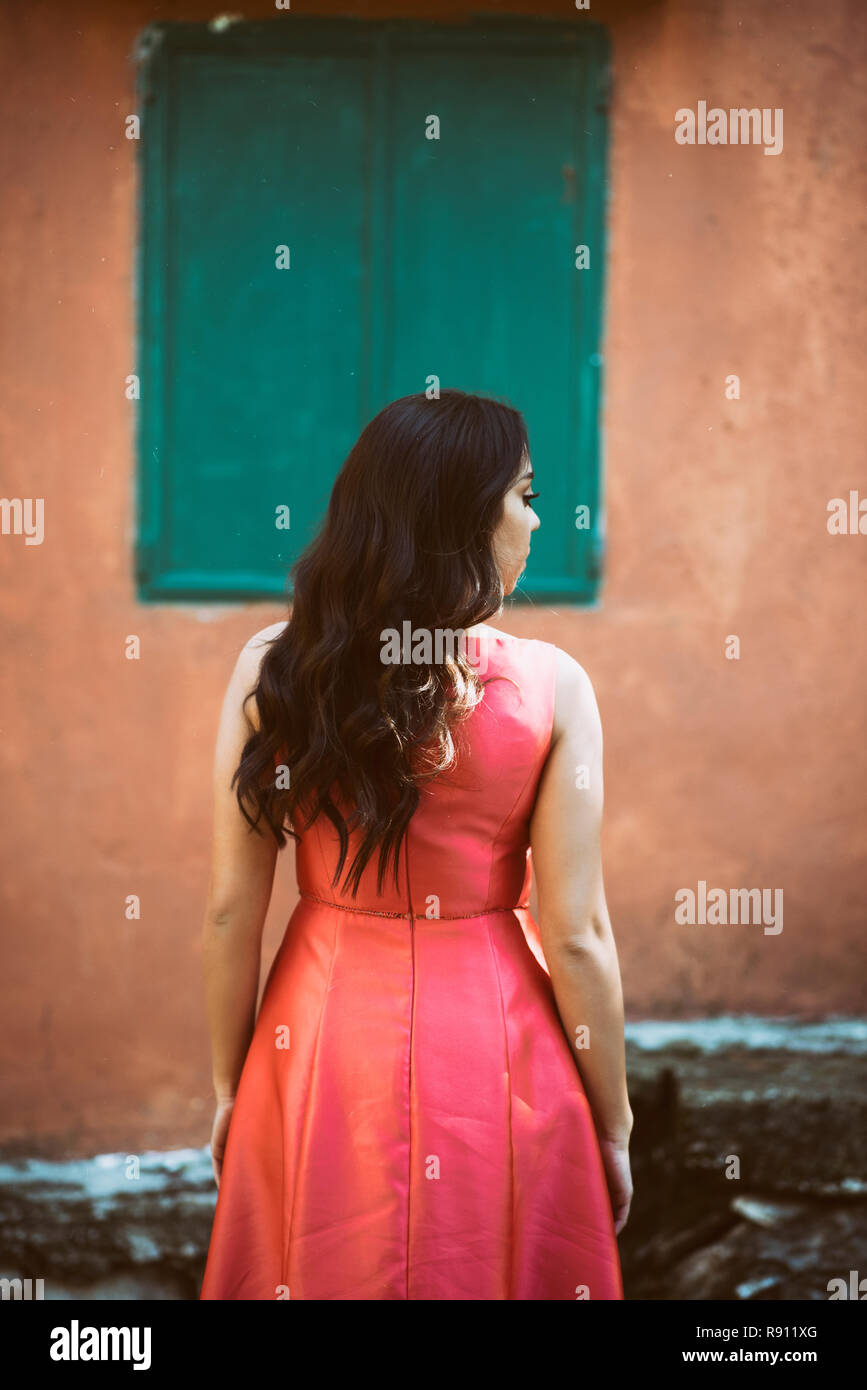 Rear view of a woman standing by the an old house looking away Stock Photo