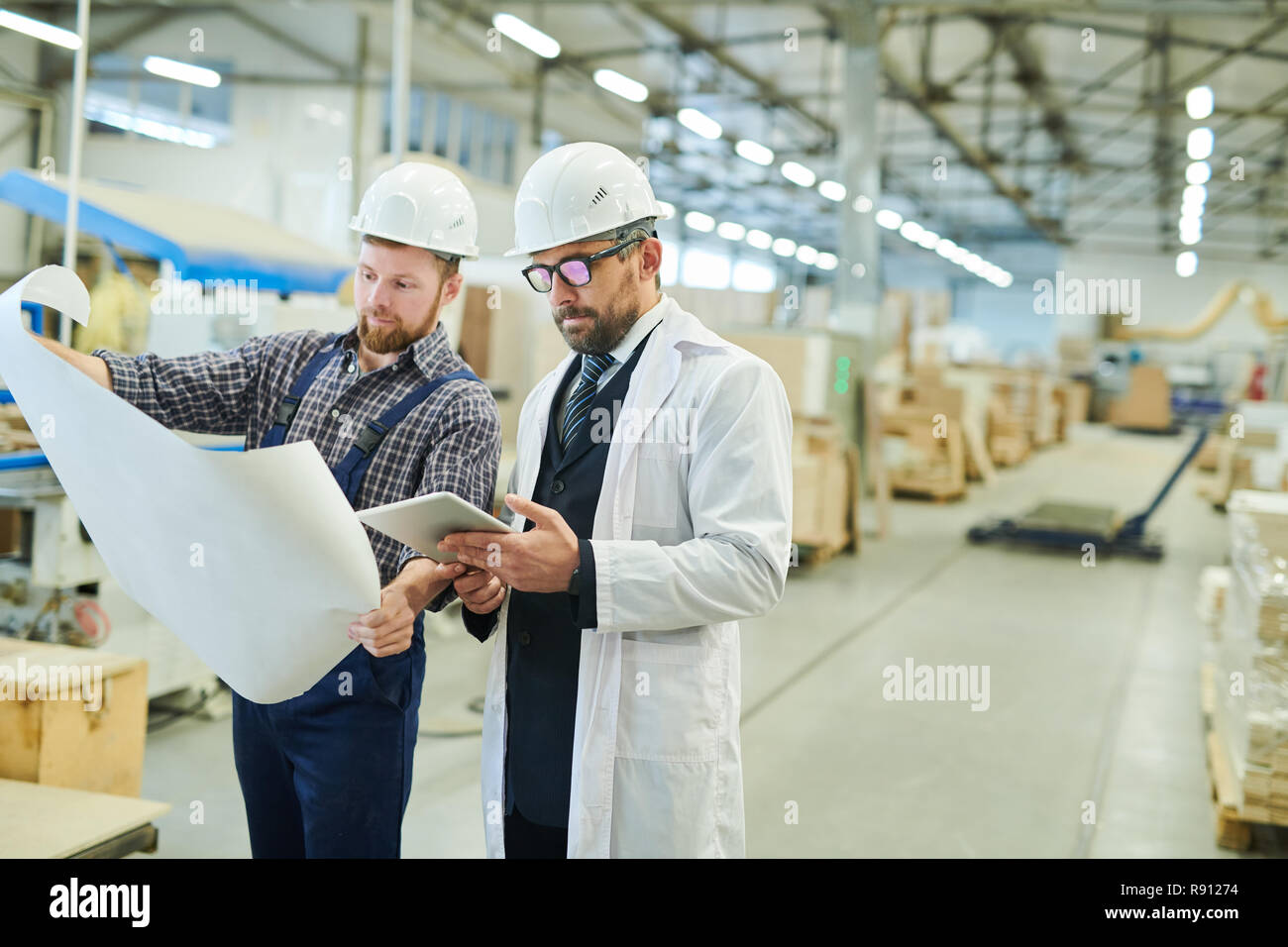 Engineers in hardhats working with project blueprint Stock Photo