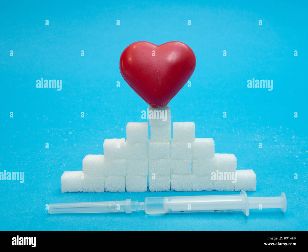 red heart on top of sugar cubes stack and syringe with injection. low level control with insulin concept Stock Photo