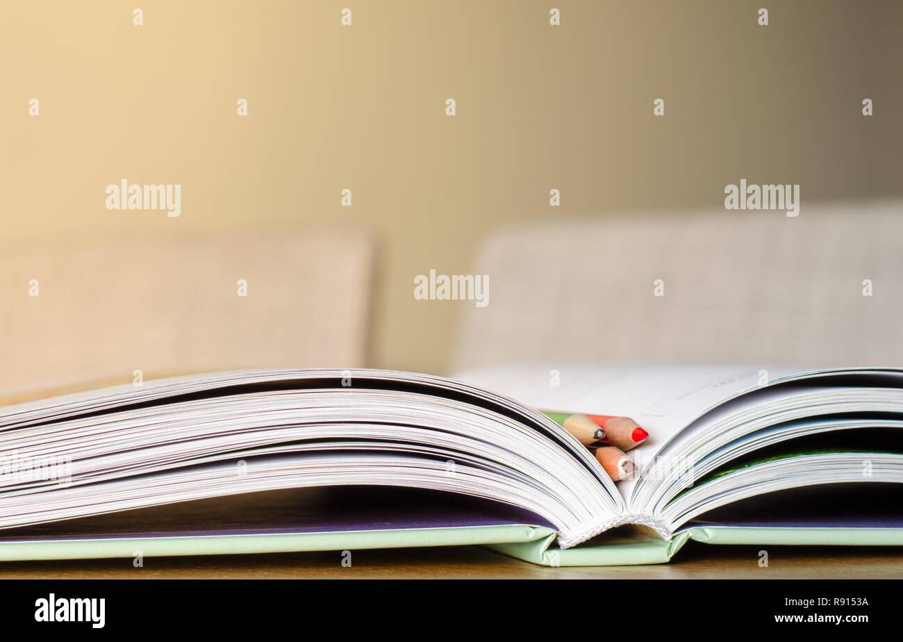 Three pencils in the open book. Reading and study theme background. Stock Photo