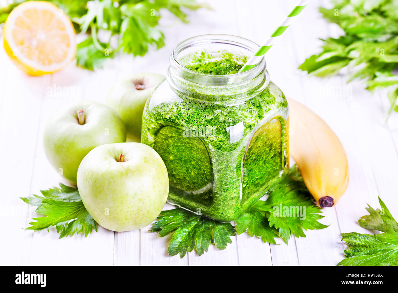Fresh green smoothie with banana, apples, celery and lemon on white table Stock Photo
