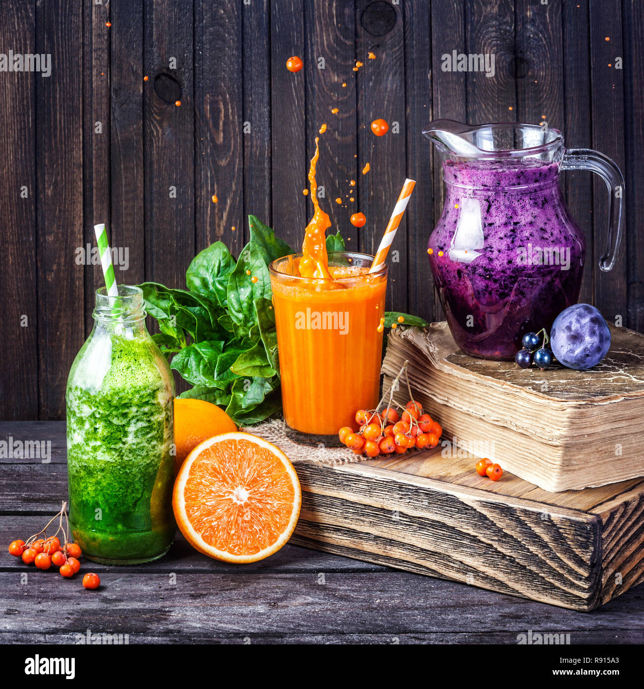 Fresh juice and smoothies with berries, fruits and green spinach on wooden background Stock Photo
