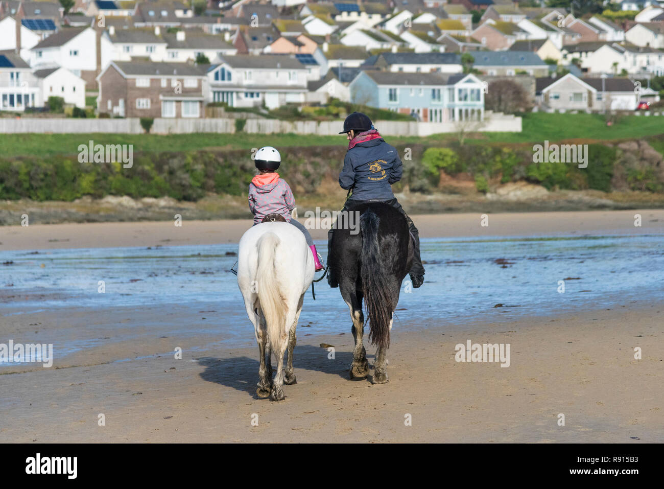 An adult and a child riding on horses in the Gannel Estuary at low tide