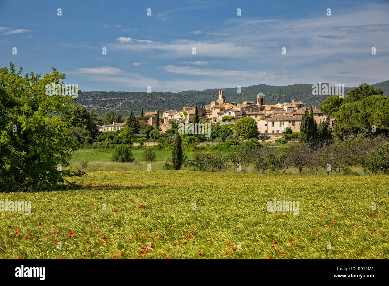 Lourmarin, a small village in the Luberon. Field of wheat and poppies with view of the idyllic village Lourmarin, Provence, Luberon, Vaucluse, France Stock Photo