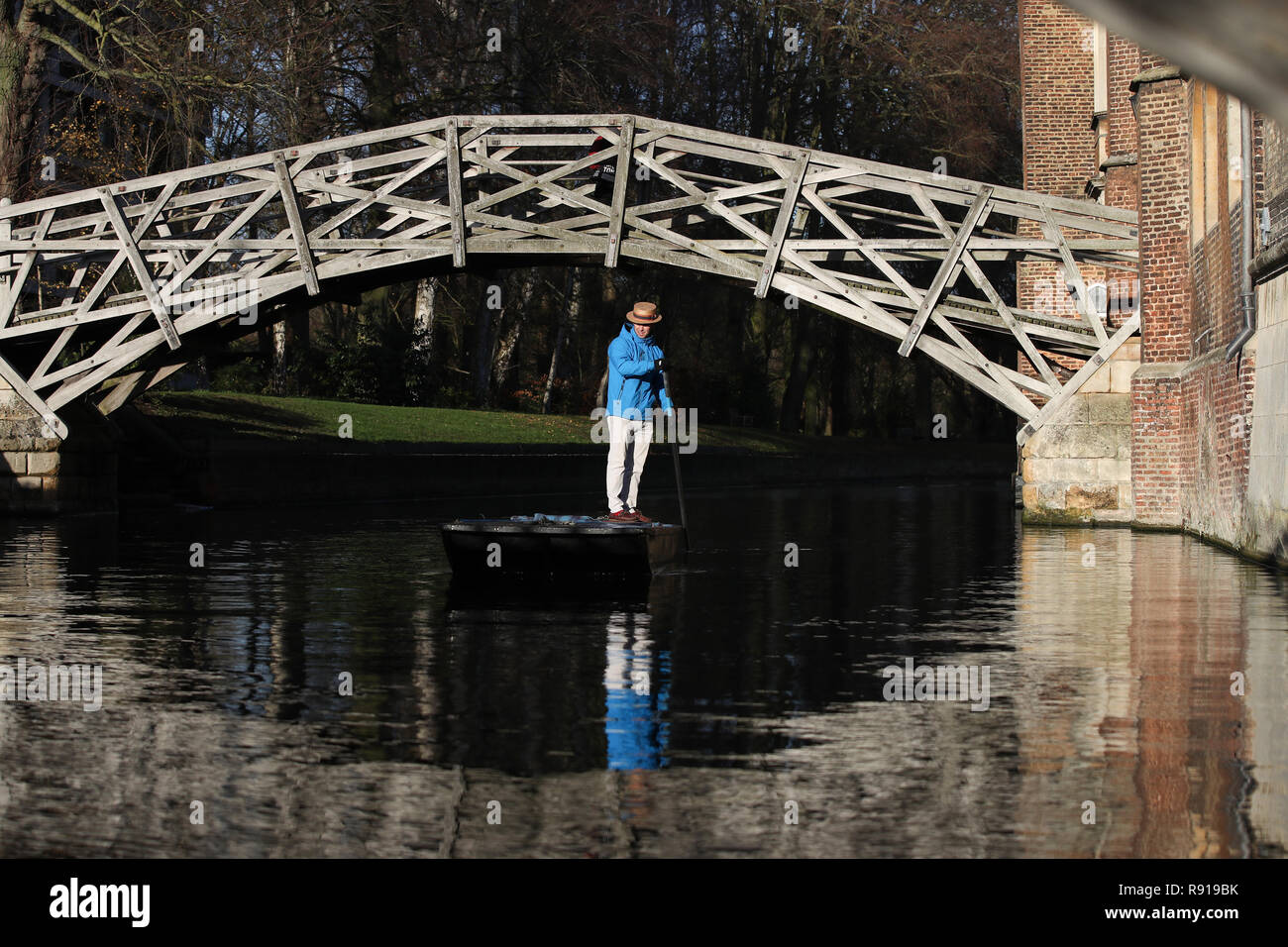 A punt chauffeur makes his way under the Mathematical Bridge at Queens College along the river Cam in Cambridge. Stock Photo