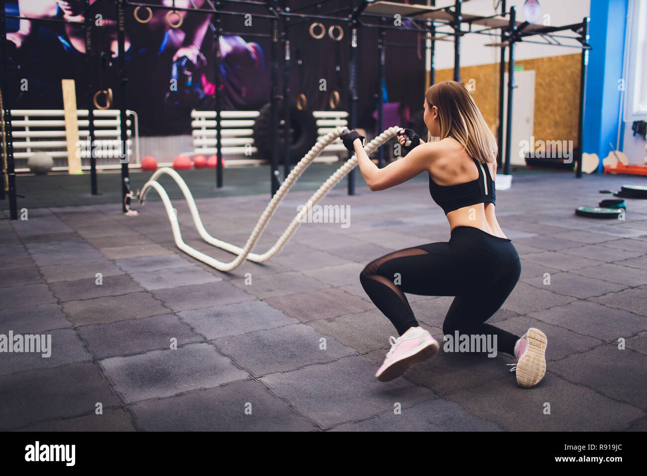 Strong Woman Exercising With Battle Ropes At The Gym