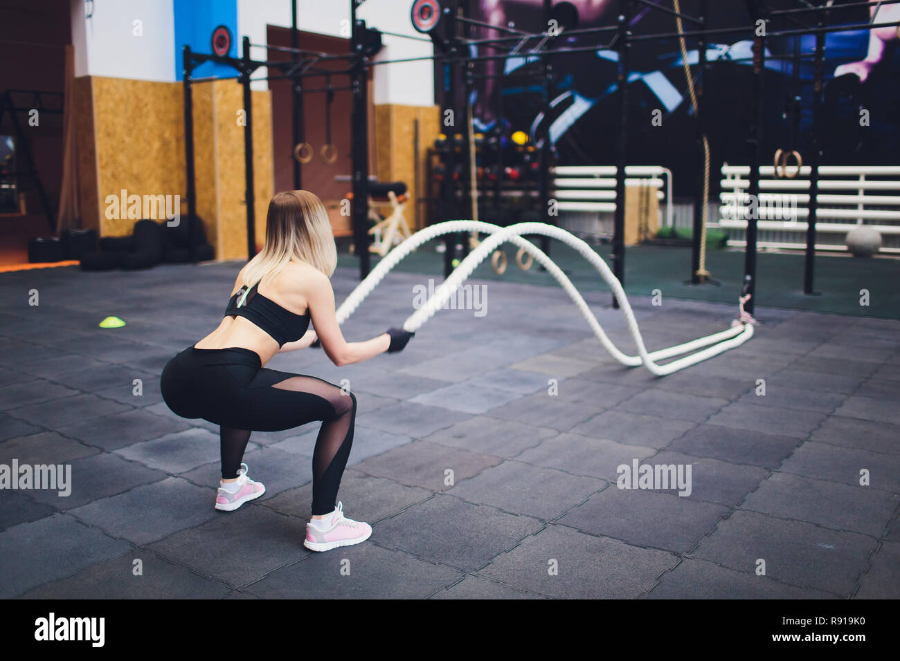 Strong woman exercising with battle ropes at the gym. Athlete doing