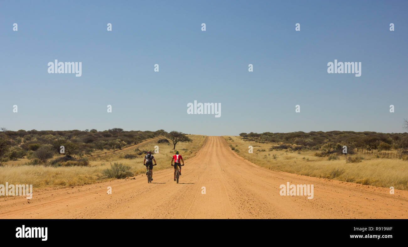 cyclists on MTB or ATB off road bike on dirt road in African landscape in Namibia Stock Photo