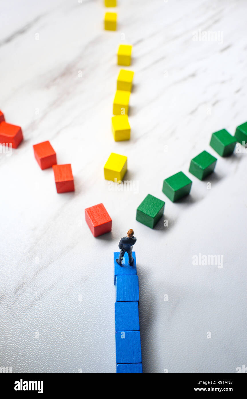 Miniature businessmen trying to pick the path to success down three