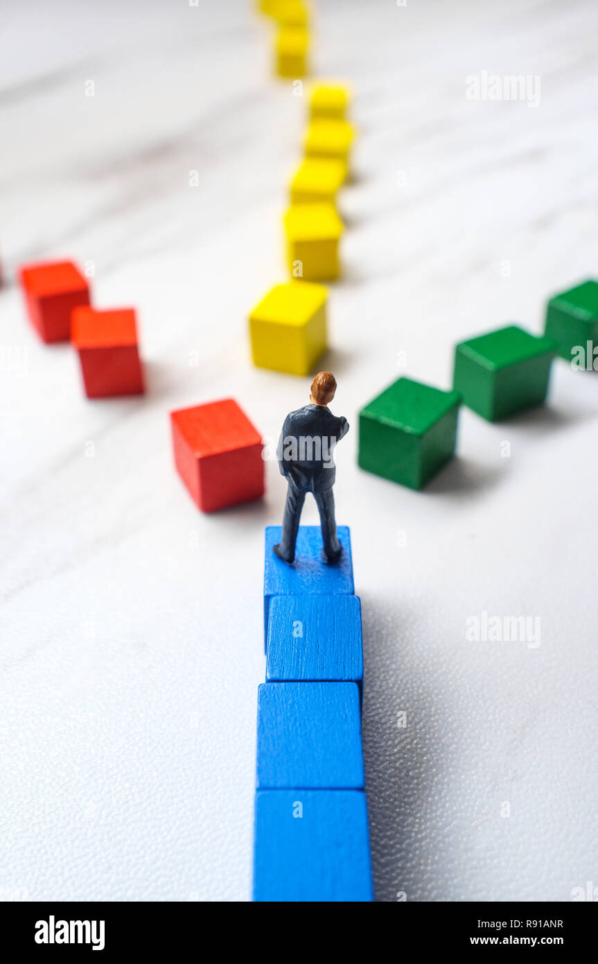 Miniature businessmen trying to pick the path to success down three