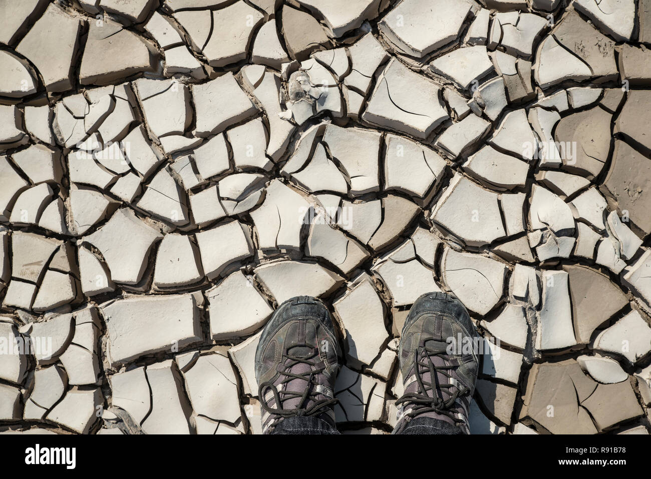 Feet stepping on dry clay of a riverbed. Representation of dry global