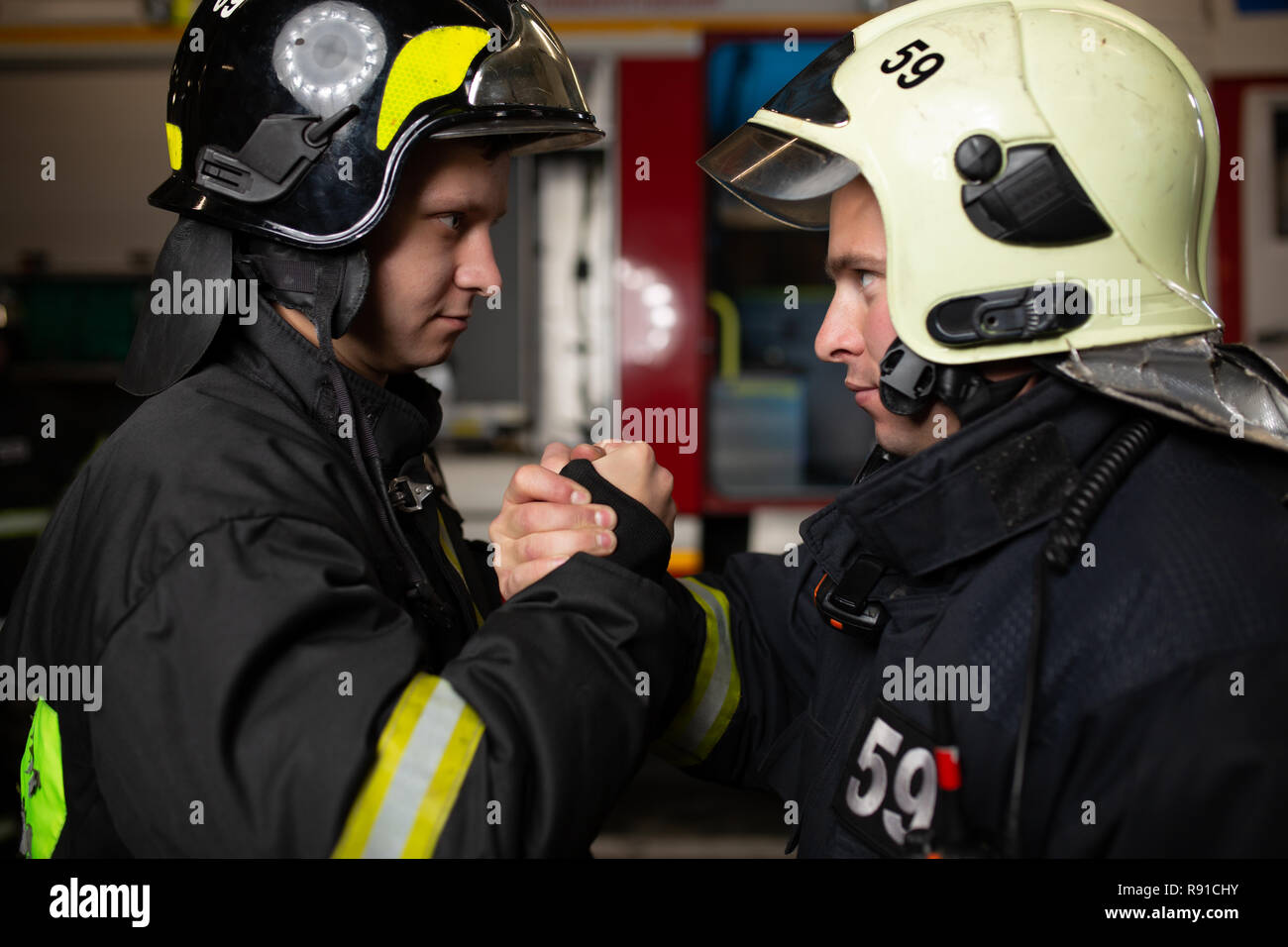 Image of two firemen wearing helmets waving their handshake Stock Photo