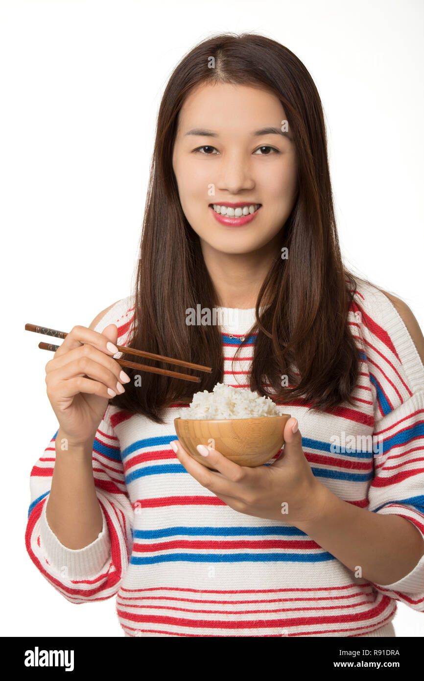 Beautiful Asian American woman eating a bowl of rice isolated on a white background Stock Photo