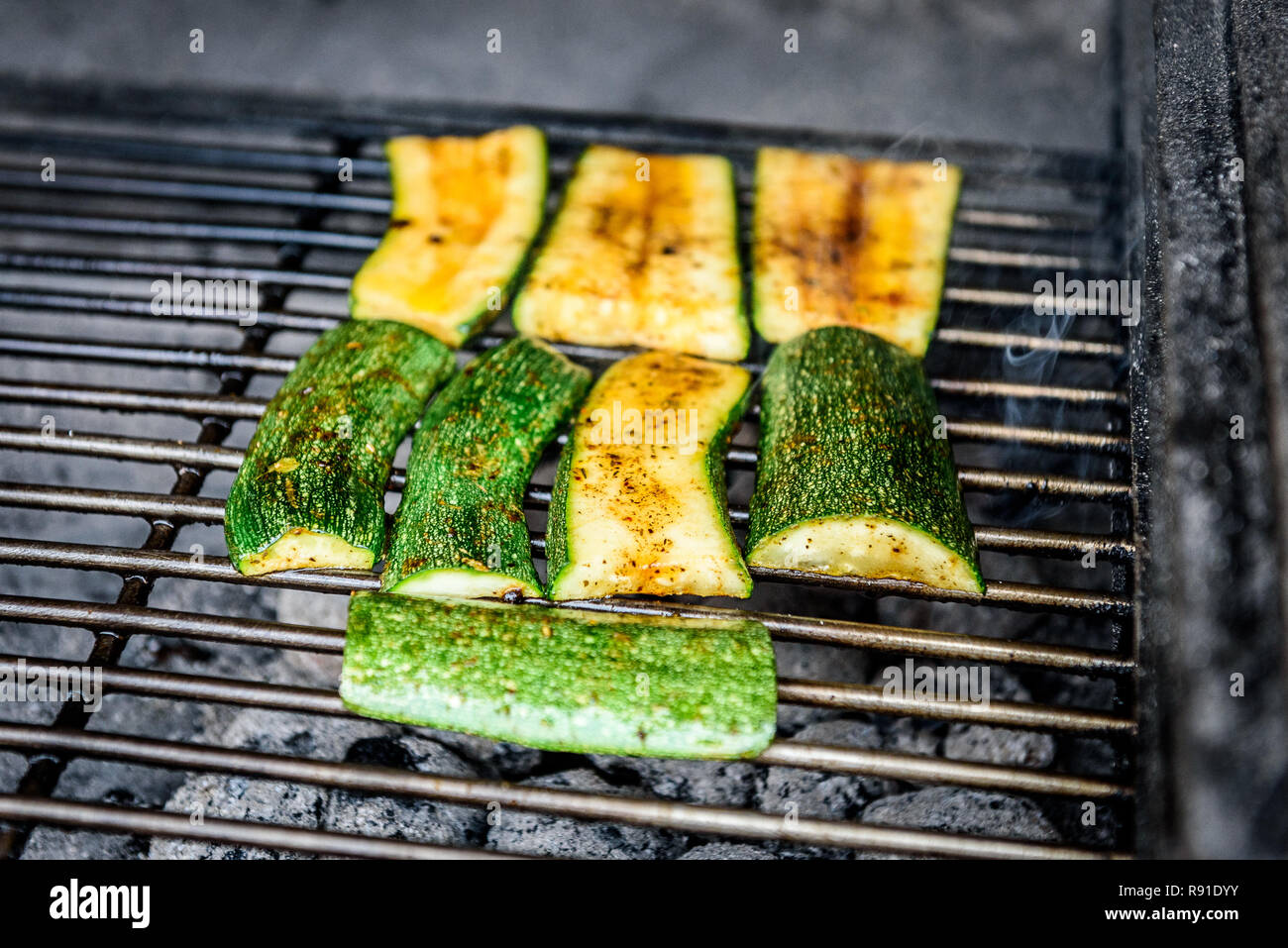 Grilling zucchini or courgette on a coal barbecue grill. Traditional Mediterranean healthy dish in prepared in barbecue fireplace. Stock Photo
