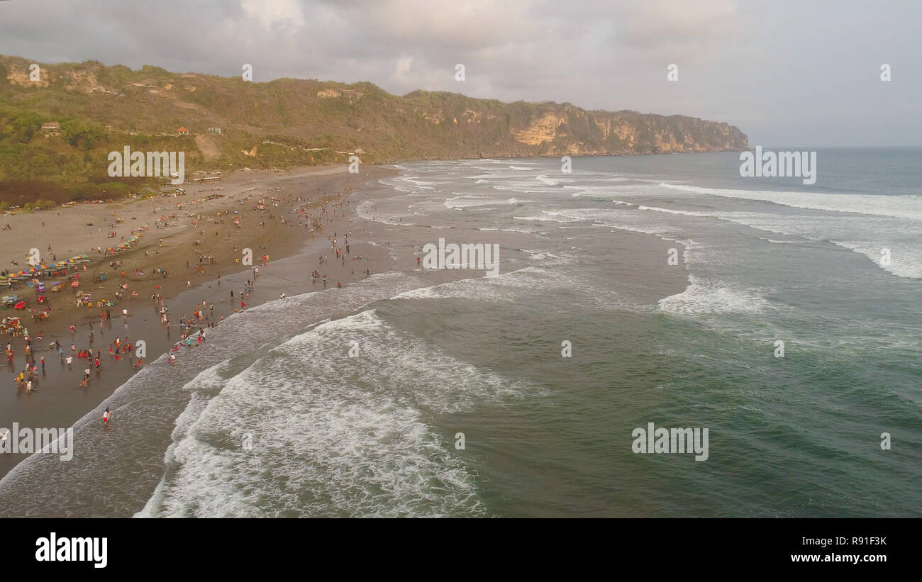 sandy beach parangtritis near ocean with big waves, people in tropical resort at sunset. Yogyakarta, Indonesia. aerial view seascape, ocean and beautiful beach. Travel concept. Indonesia, jawa Stock Photo