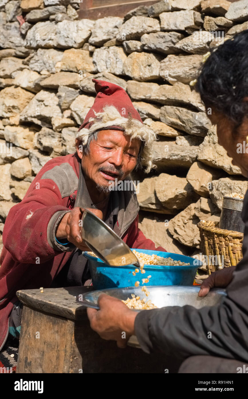 Tibetan trader measuring out corn, Nepal, Himalayas Stock Photo