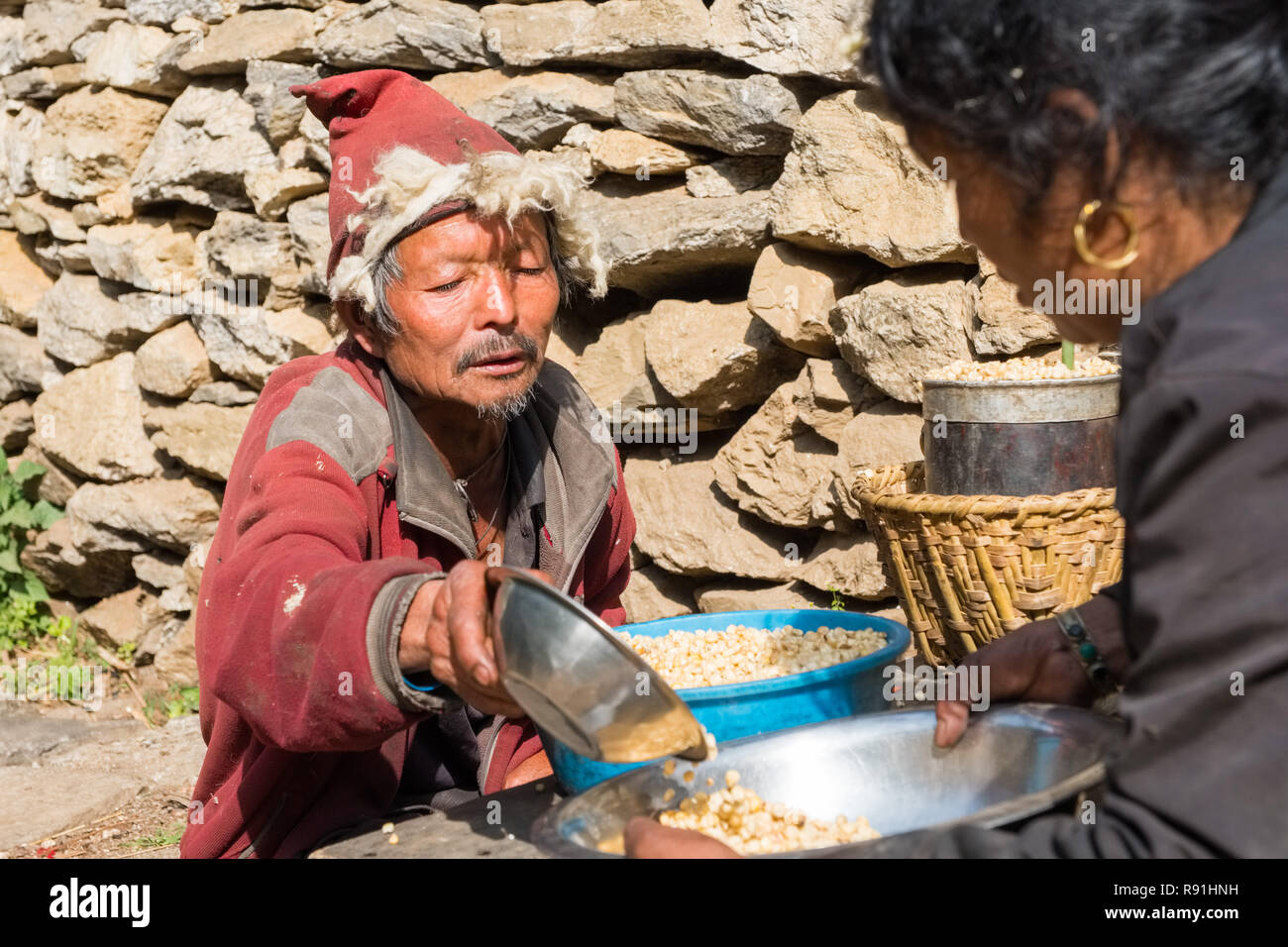 Tibetan trader measuring out corn, Nepal, Himalayas Stock Photo