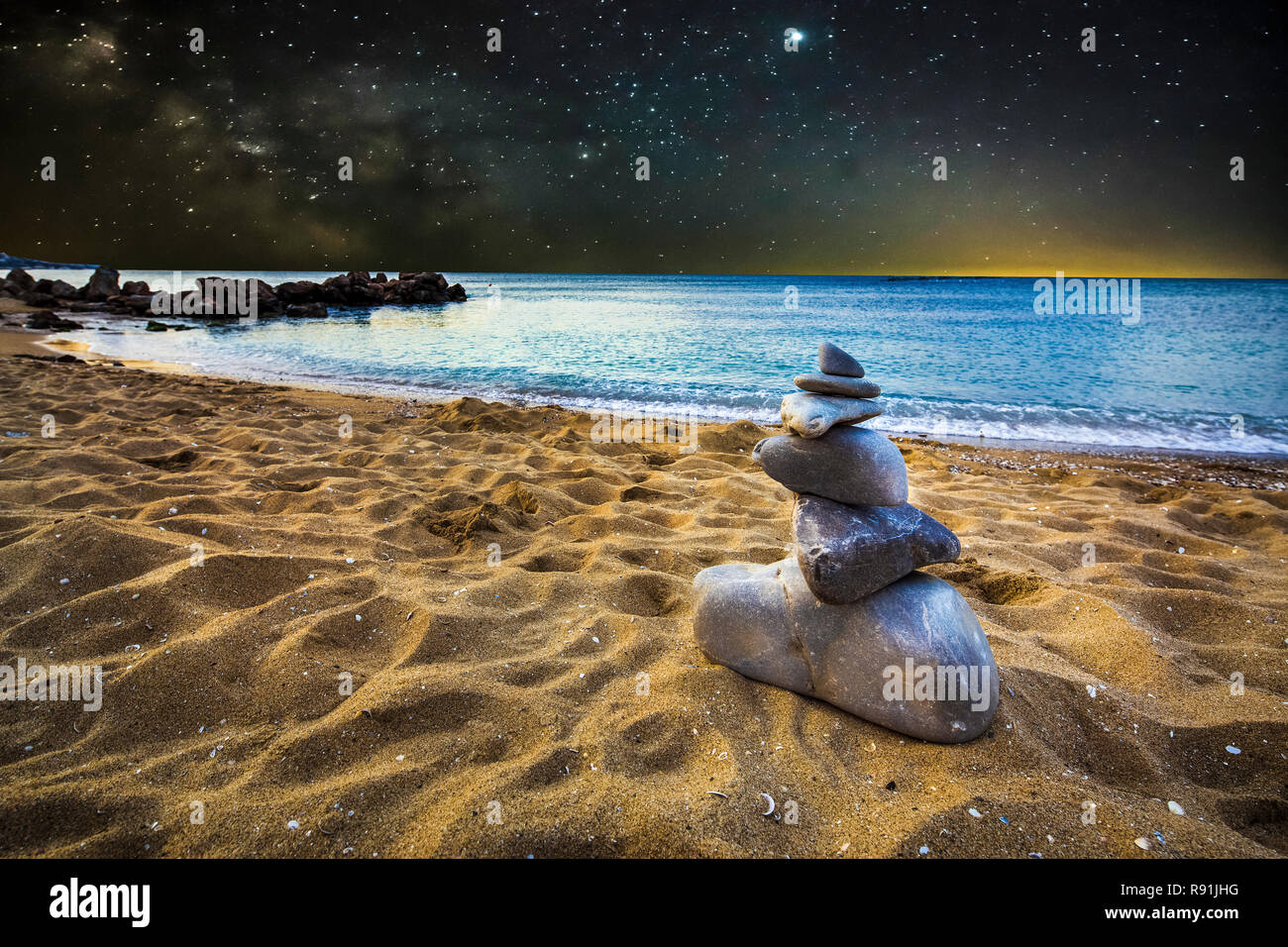 stone cairn on the sand beach, on the background  of night star landscape, concept of balance Stock Photo