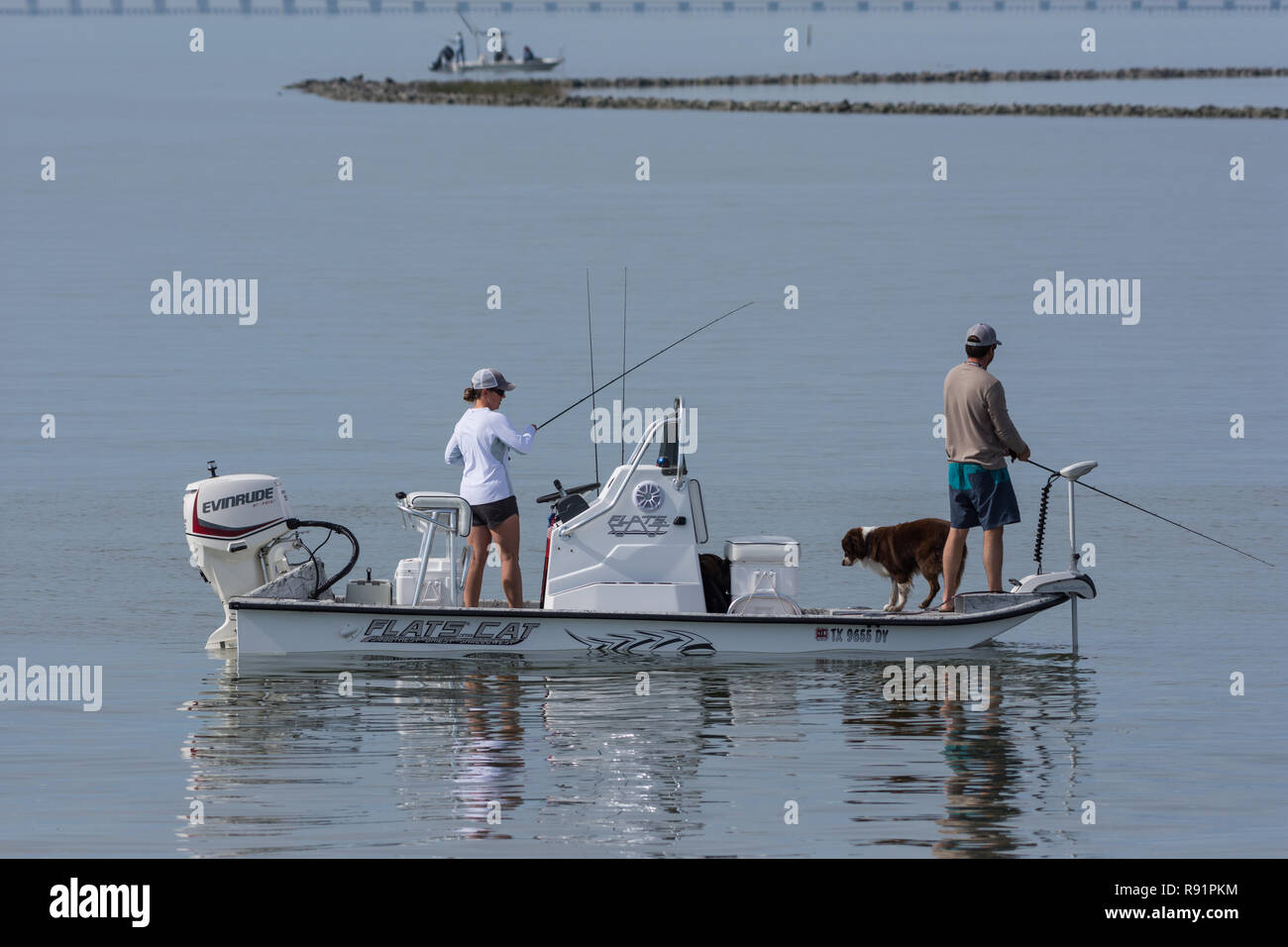 A couple fishing on a boat with their dog. Aransas National Wildlife Refuge, Texas, USA. Stock Photo