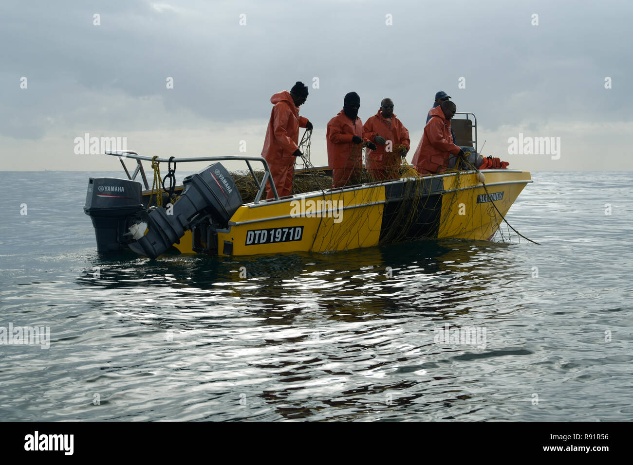 Workers of Natal Sharks Board on yellow boat, checking condition of anti shark net to ensure swimmer safety, Durban, KwaZulu-Natal, South Africa Stock Photo