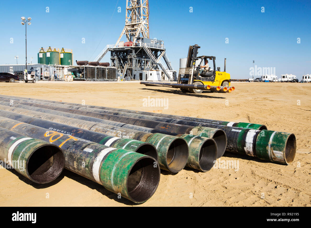 Man in forklift carrying pipes during drilling operations for oil in