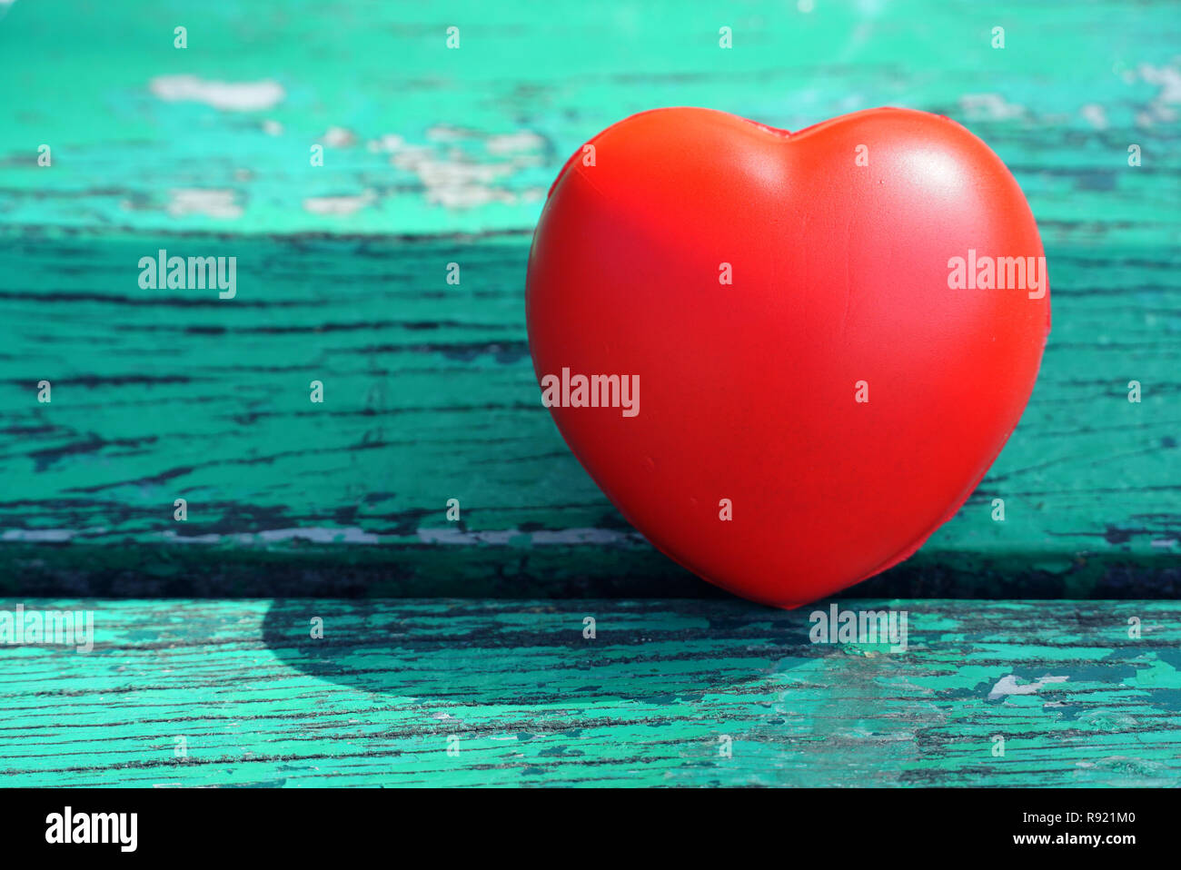 Red heart on green wood background Stock Photo - Alamy