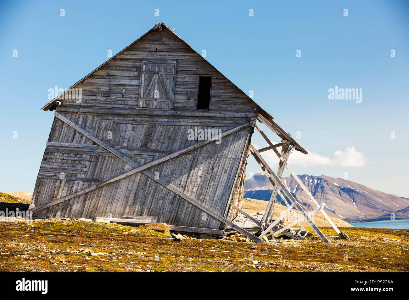 An old house at Recherchefjorden (77Ãáẁ31ÃḃÂn 14Ãáẁ36ÃḃÂe), Van Keulenfjorden, Spitsbergen, Svalbard. It is gradually sliding down slope due to solifluction and permafrost melt. Climate change is accelerating permafrost melt and causing huge damage across the Arctic. It is also one of the feedback loops that exascerbate climate change, as the permafrost locks away billions of tonnes of methane (a greenhouse gas 23 times more potent than C02), as the permafrost melts this methane is released into the atmosphere with porentially disastrous consequences. Stock Photo