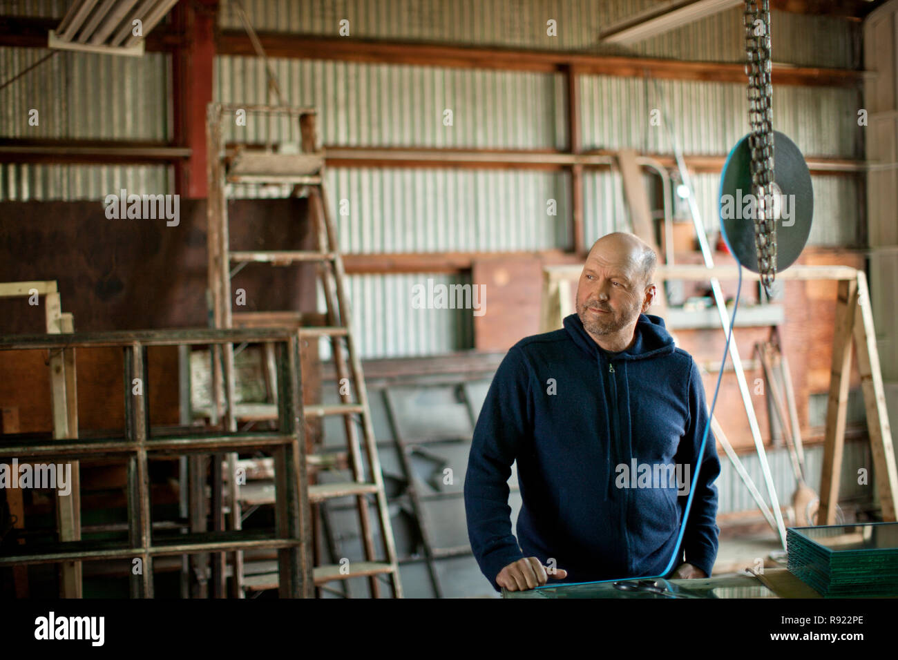Mid adult man looking thoughtful while standing in a workshop. Stock Photo