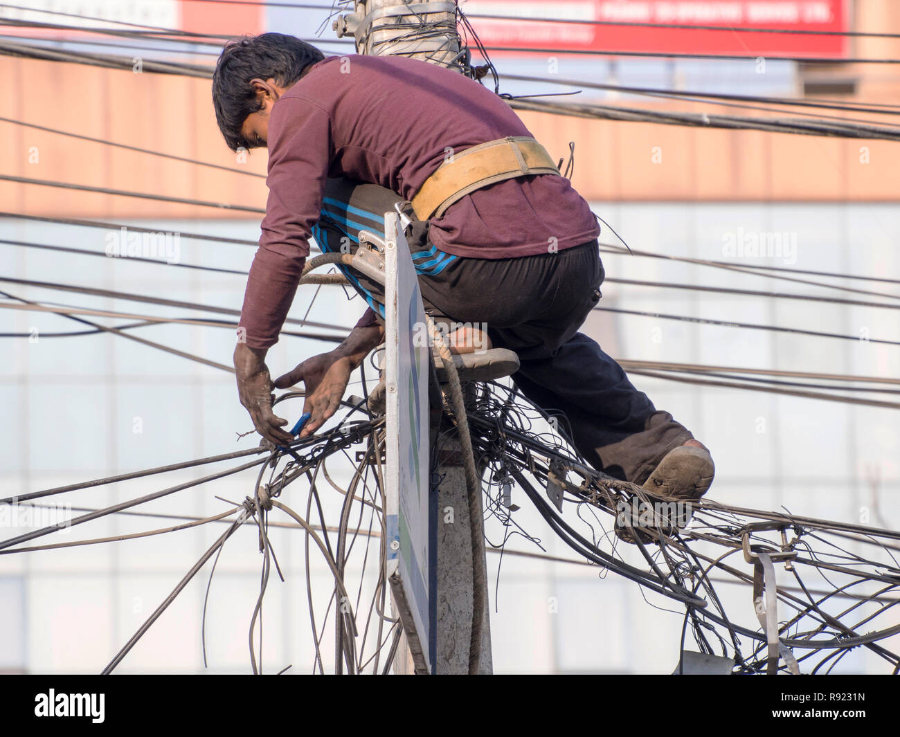 Electrician trying to untangle power lines on top of utility pole, Kathmandu, Nepal Stock Photo