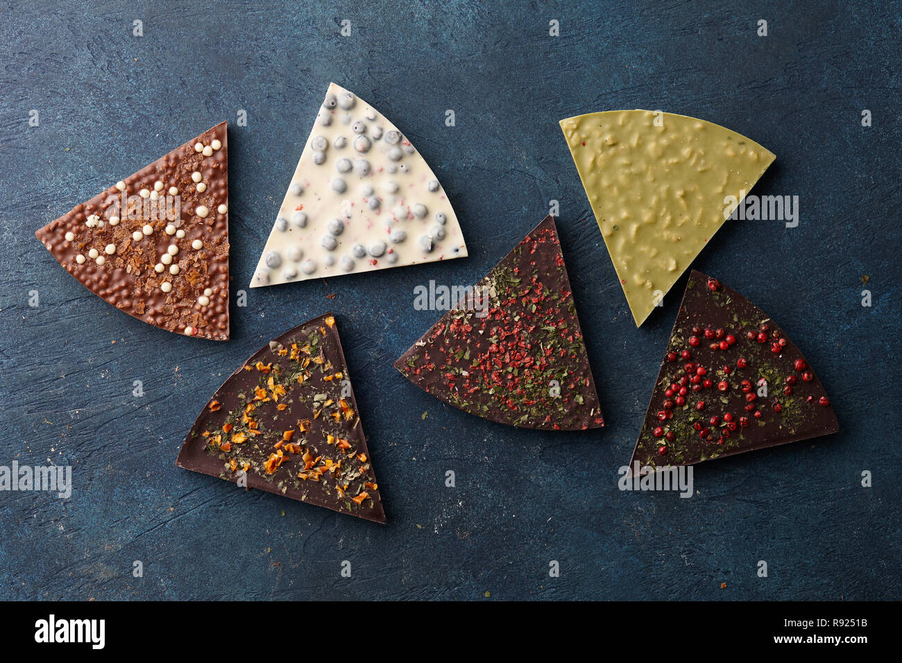 Triangle shape chocolate pizza slices with diverse kinds of toppings on blue background, top view Stock Photo